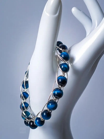 Blue Tiger Eye gemstone bracelet with silver-plated copper wires, displayed on a mannequin hand