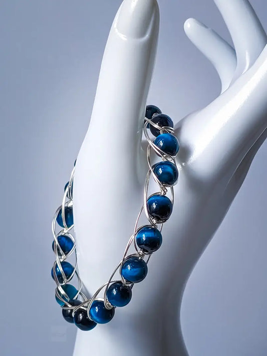 Blue Tiger Eye gemstone bracelet with silver-plated copper wires, displayed on a mannequin hand