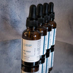 4 amber dropper bottles of beard oil in a diagonal row with the Bamboo Woods bottle at the front