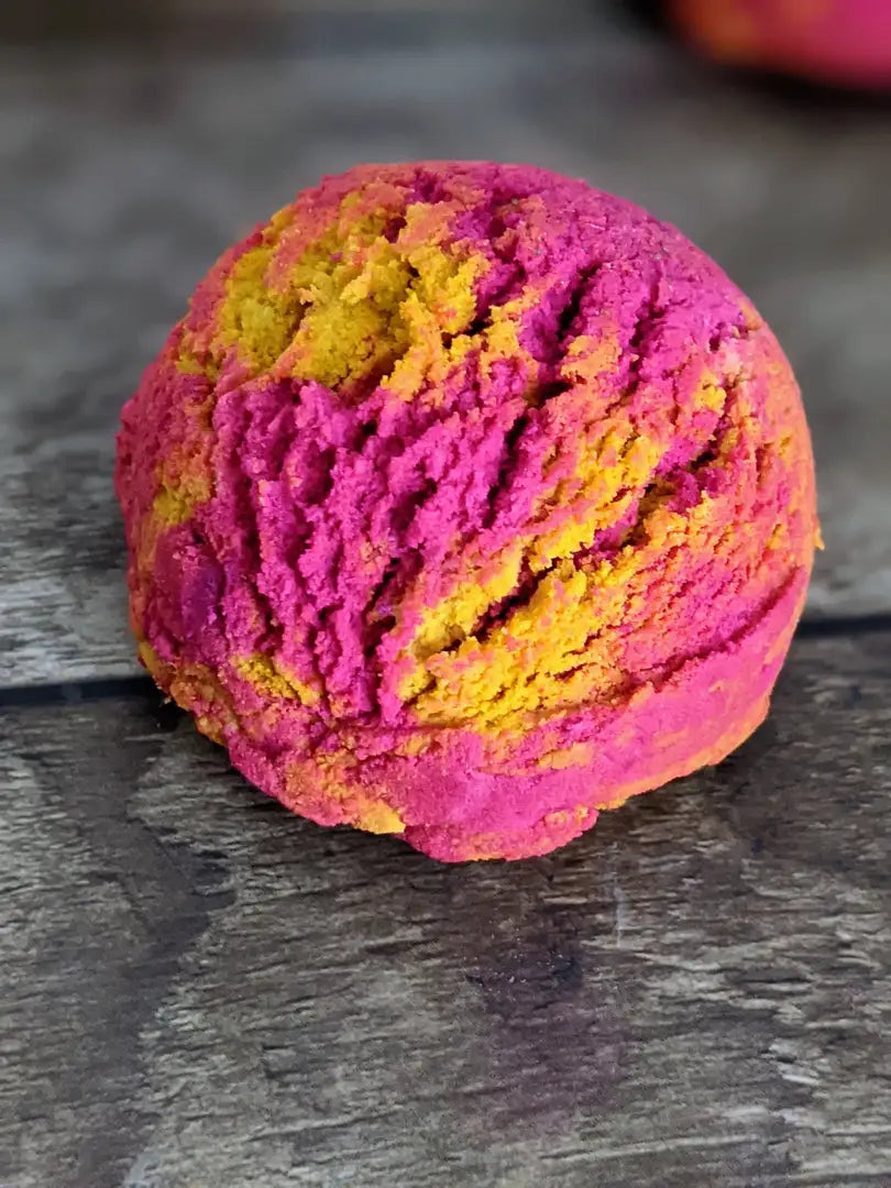 1 round bubble scoop with pink & yellow swirls, and placed on a wood grain background.