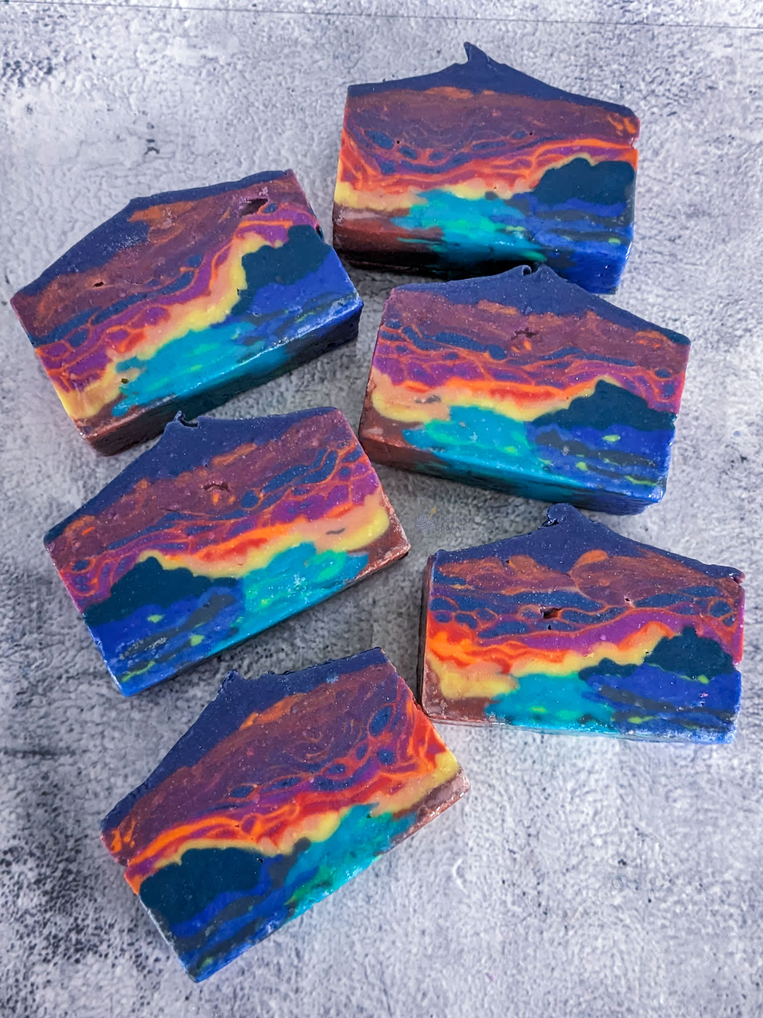 6 bars of soap designed to look like an abstract neon sunset over a vibrant blue/green ocean .